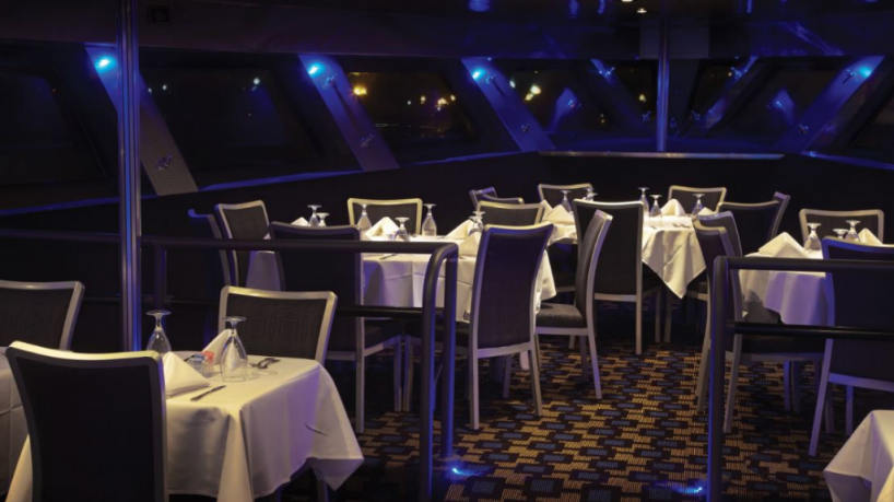 Elegant yacht dining area with tables and ambient blue lighting.